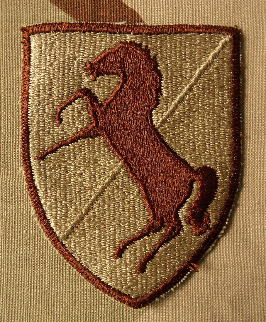 Schildförmiges Patch des 11th Armored Cavalry Regiment der US-Armee beige mit einem springenden braunen Pferd in der Mitte