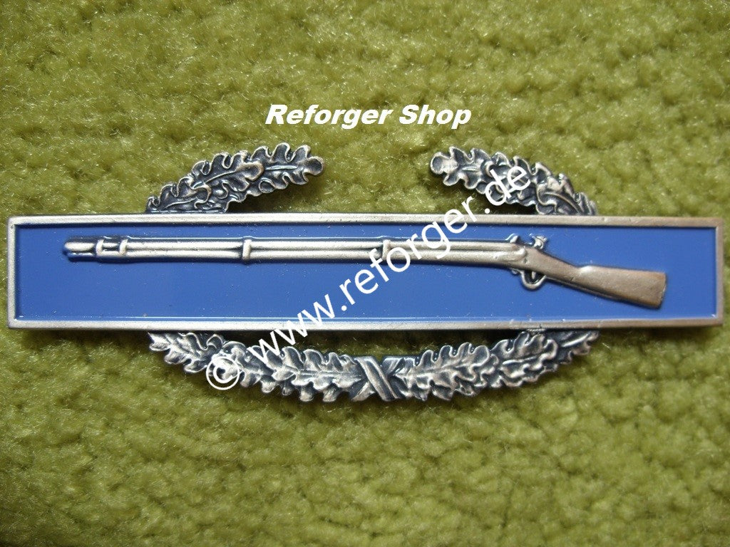 Der "CIB" Combat Infantryman Anstecker Badge zeigt ein stilisiertes Gewehr (M1 Garand) und einen Eichenkranz, der das Abzeichen umgibt.